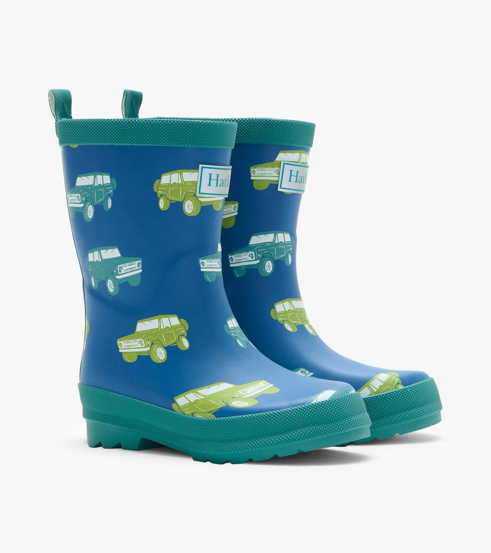 Pair of blue matte rain boots with green trim and vintage truck print, angled front view