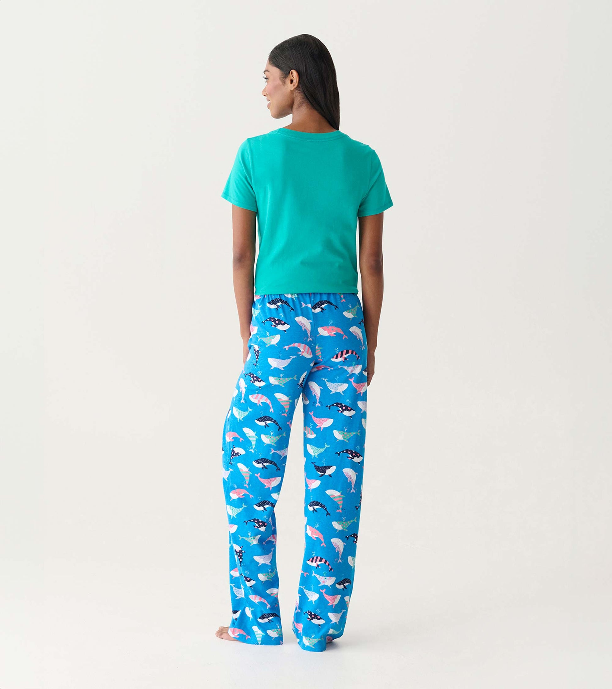 Back view of blue cotton pajama pants with colorful whale print, worn with a teal T-shirt