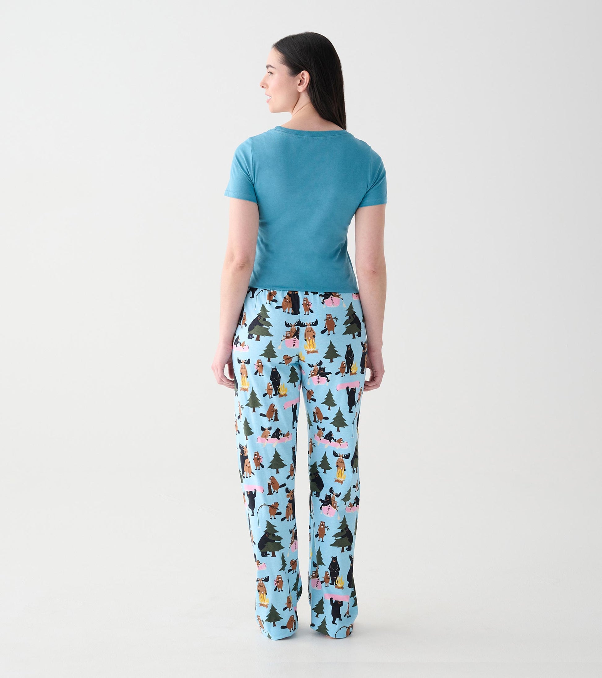 Back view of light blue pajama pants with woodland animal, tree, and campfire print on model