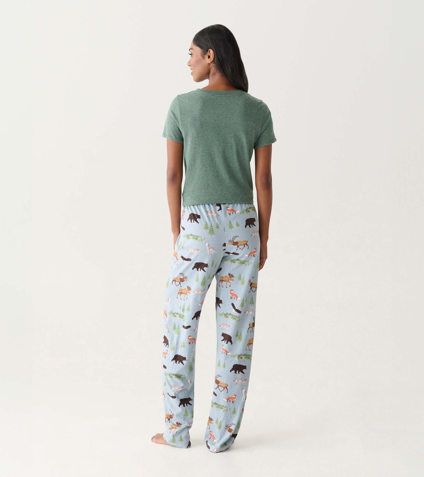 Back view of light blue pajama pants with forest animal print, worn with a green short-sleeve top