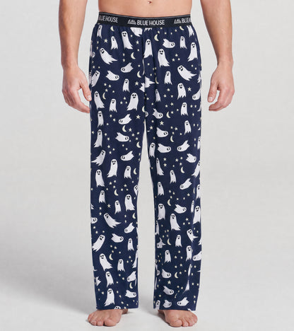 Front view of navy pajama pants with white ghosts, stars and crescent moons, worn by model