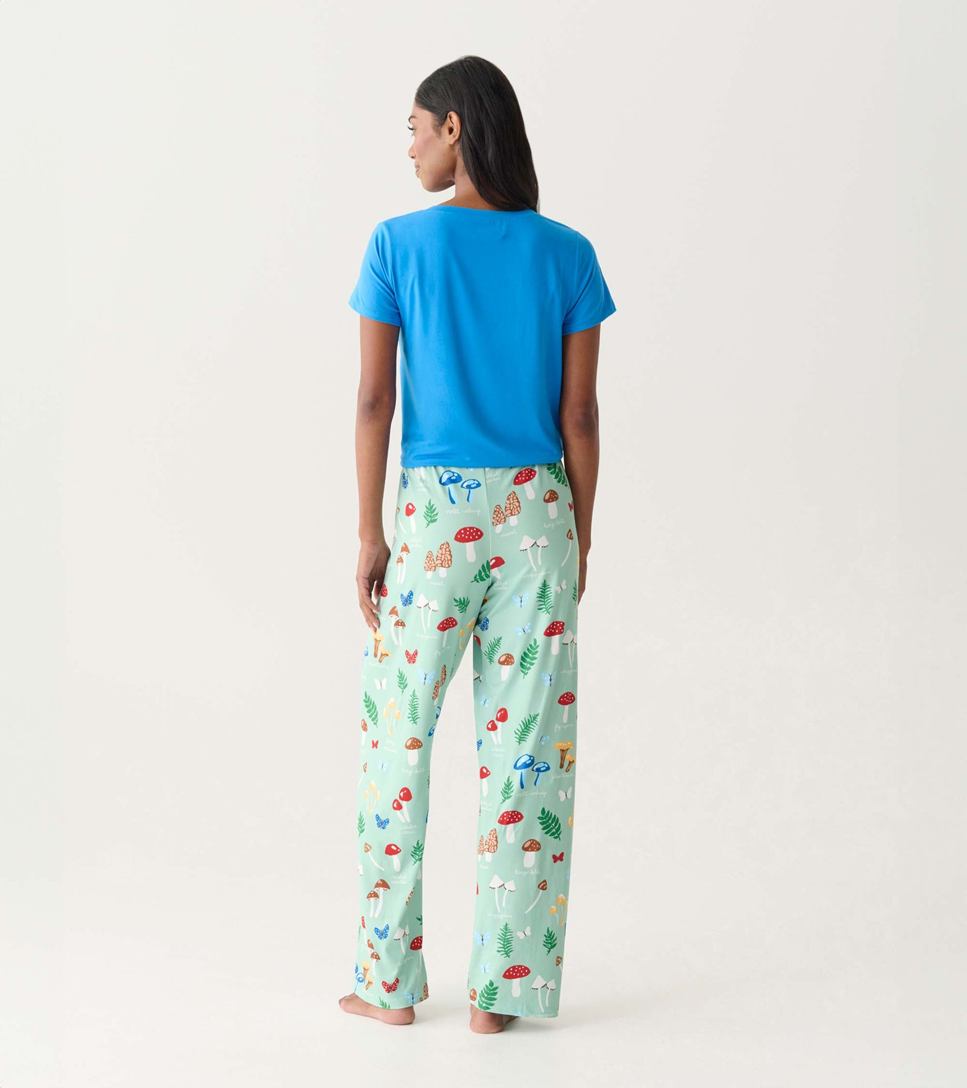 Back view of mint green pajama pants with colorful mushroom print, worn with a blue T-shirt.