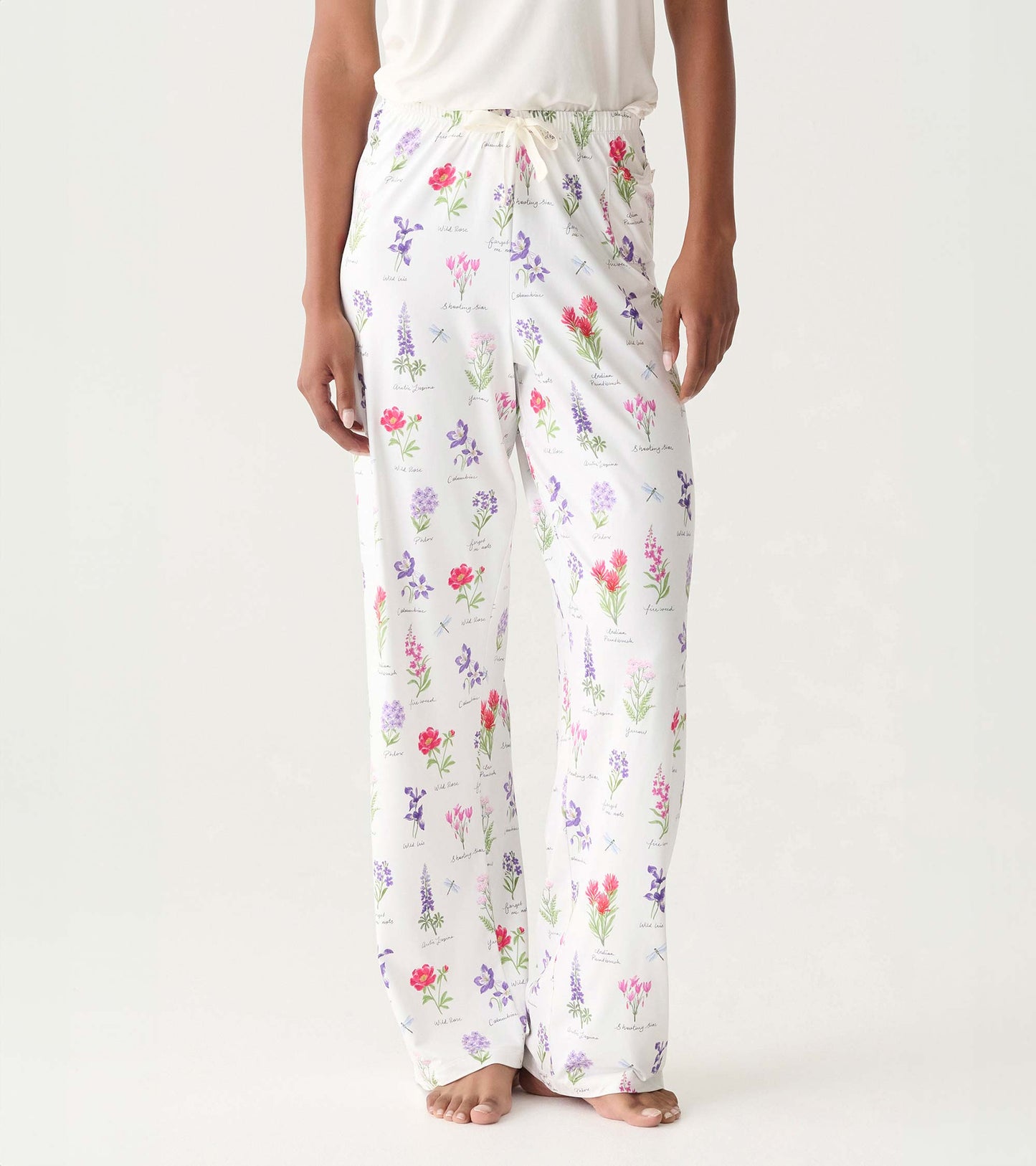 White pajama pants with colorful wildflower print and drawstring waist, shown on model front view