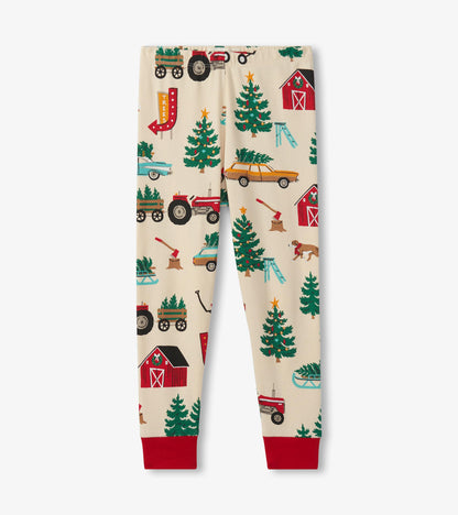 Cream pajama pants featuring a festive Christmas tree farm print with tractors, trees, and barns, finished with red cuffs.