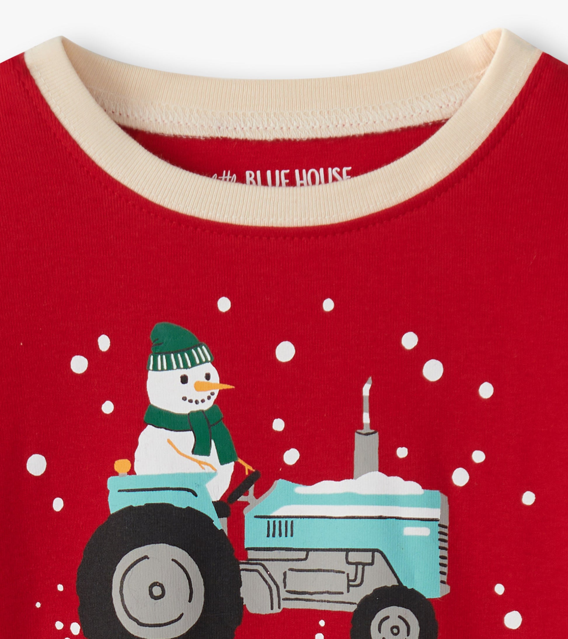 Red pajama top featuring a snowman on a blue tractor with snowflakes, designed for kids.