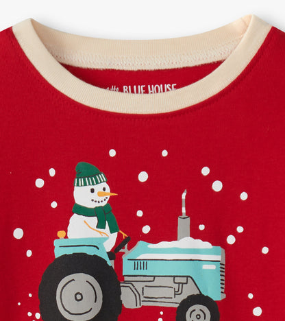 Red pajama top featuring a snowman on a blue tractor with snowflakes, designed for kids.