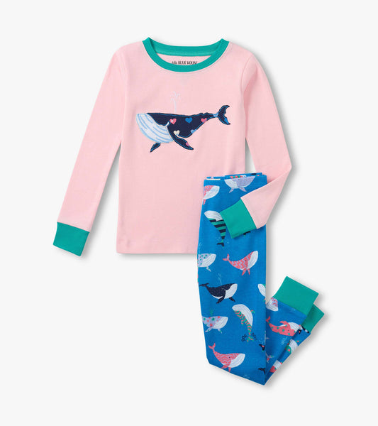 Girls pink long-sleeve pajama top with whale graphic and blue whale-print pants with teal cuffs, laid flat
