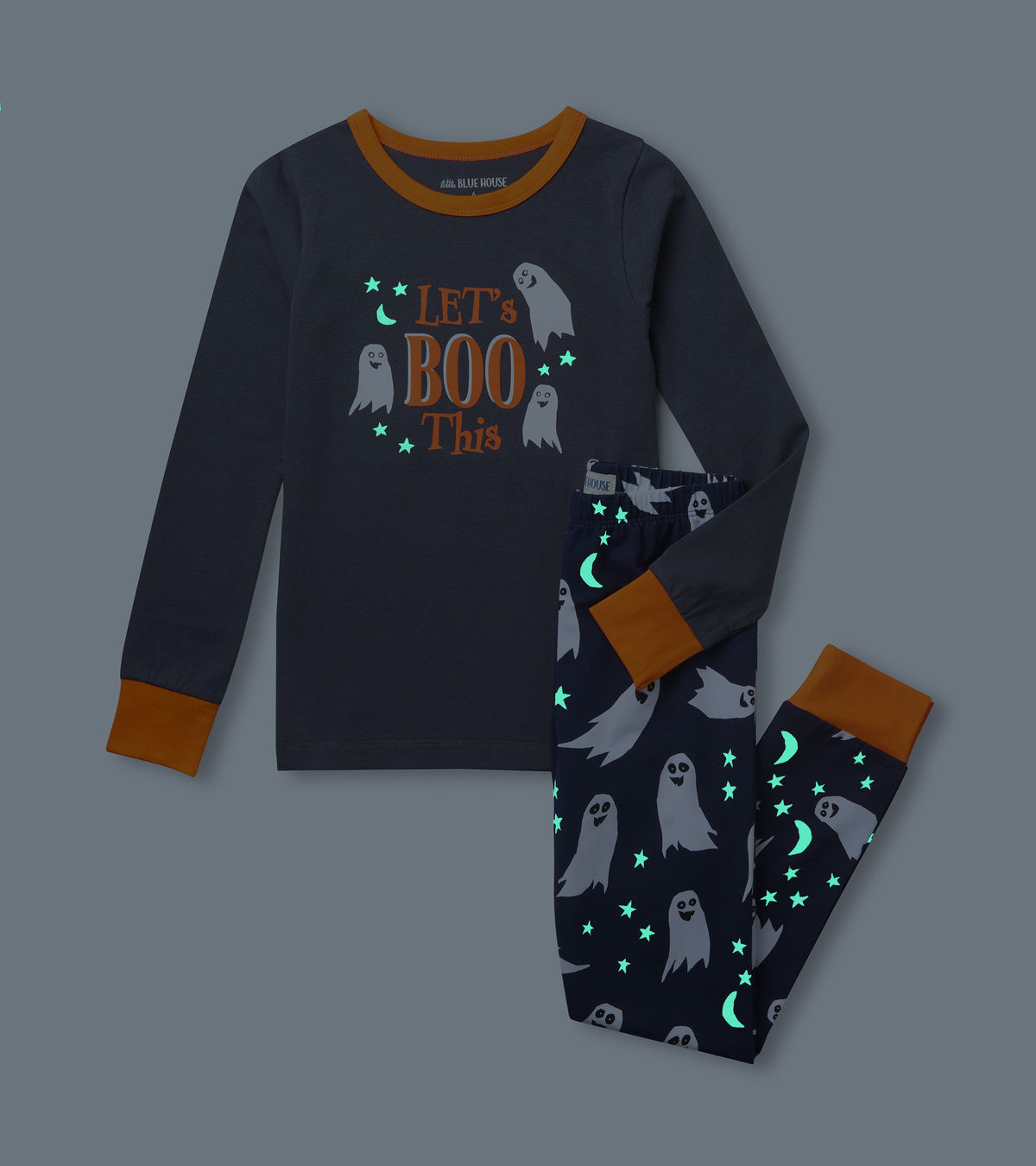 Kids pajama set shown in the dark with glowing stars and moons on ghost print pants and 'Let's Boo This' top