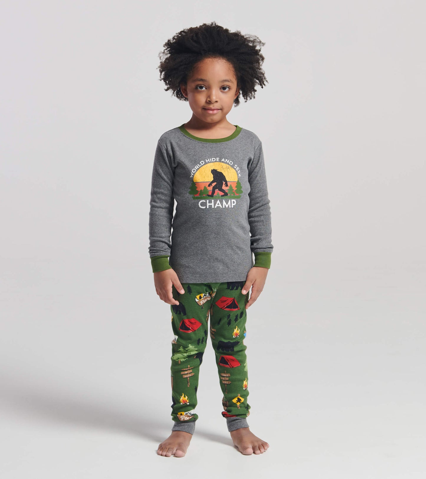 Gray long-sleeve pajama top with green trim and a camp-themed print on green pants featuring tents and trees.