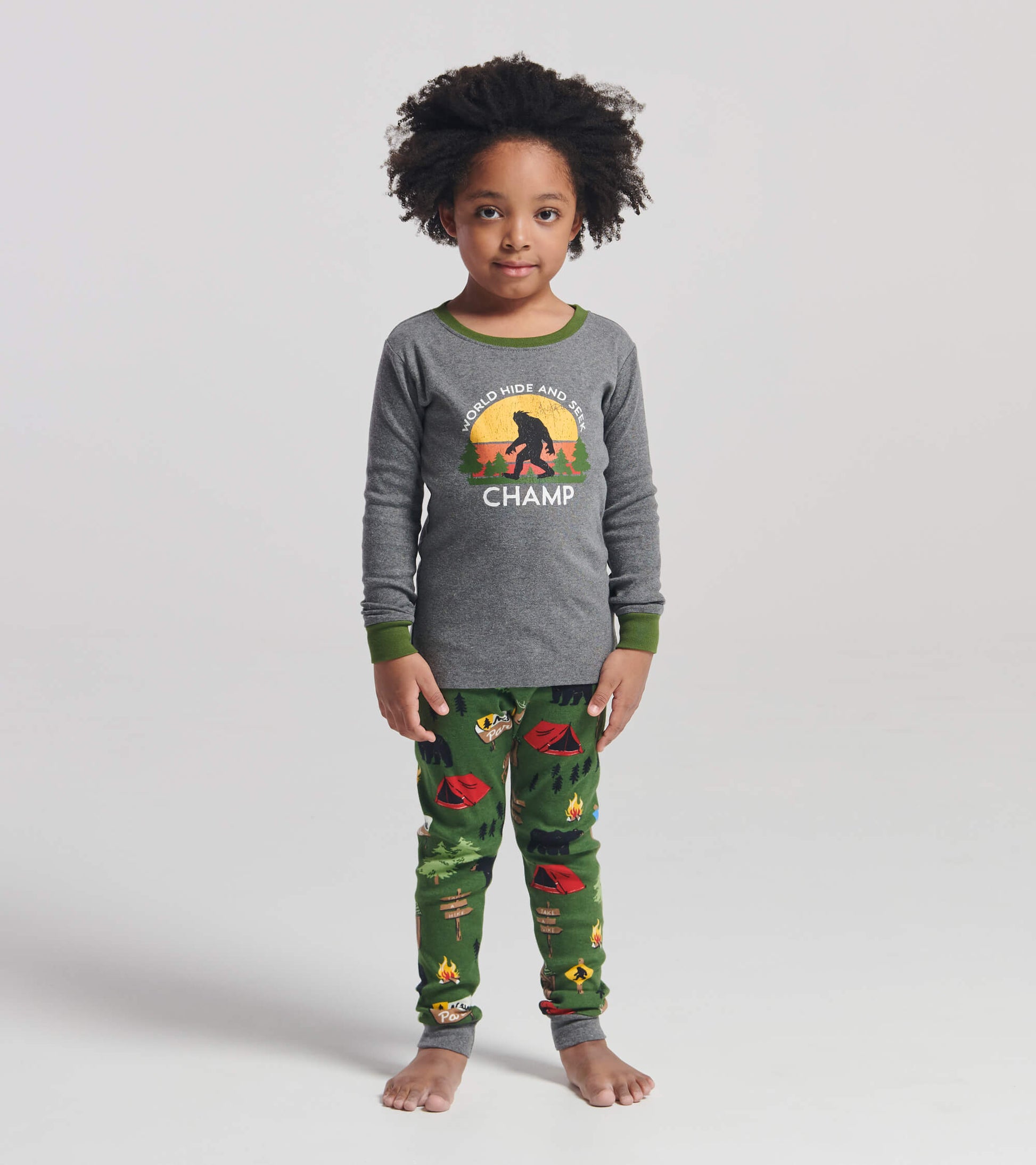 Gray long-sleeve pajama top with green trim and a camp-themed print on green pants featuring tents and trees.