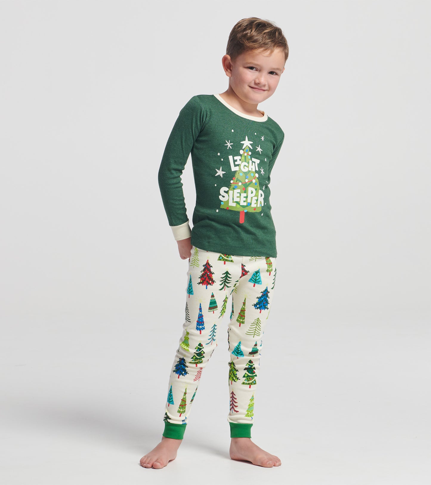 Green long-sleeve pajama top with "Light Sleeper" text, paired with cream pants featuring colorful Christmas tree patterns.