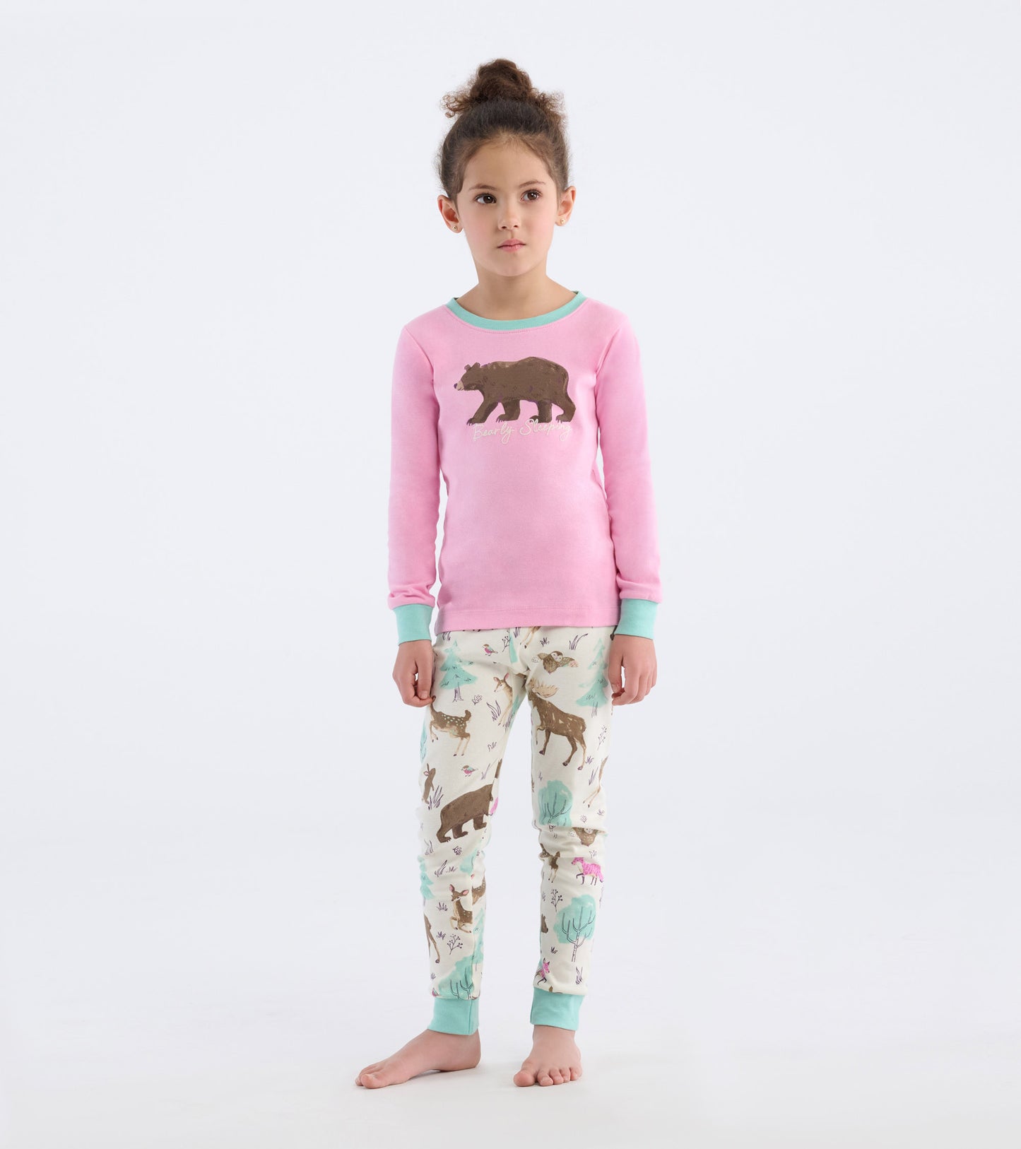 Pink long-sleeve pajama top with bear graphic paired with cream pants featuring animal prints and mint green cuffs.