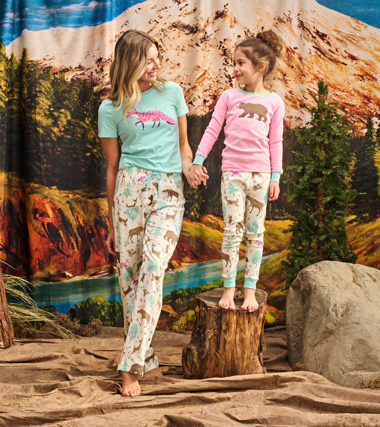 Matching girls' pajama set featuring a pink bear graphic top and patterned pants with woodland animals and cacti.