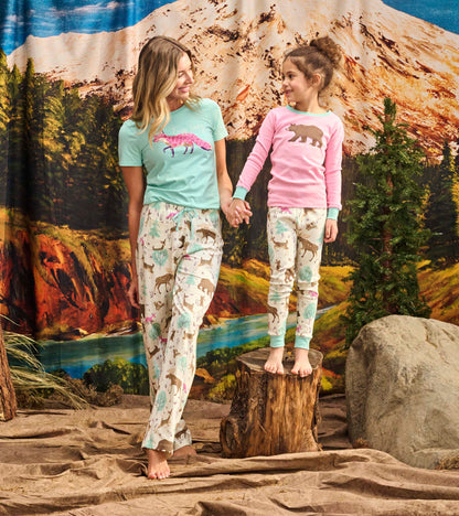 Matching girls' pajama set featuring a pink bear graphic top and patterned pants with woodland animals and cacti.