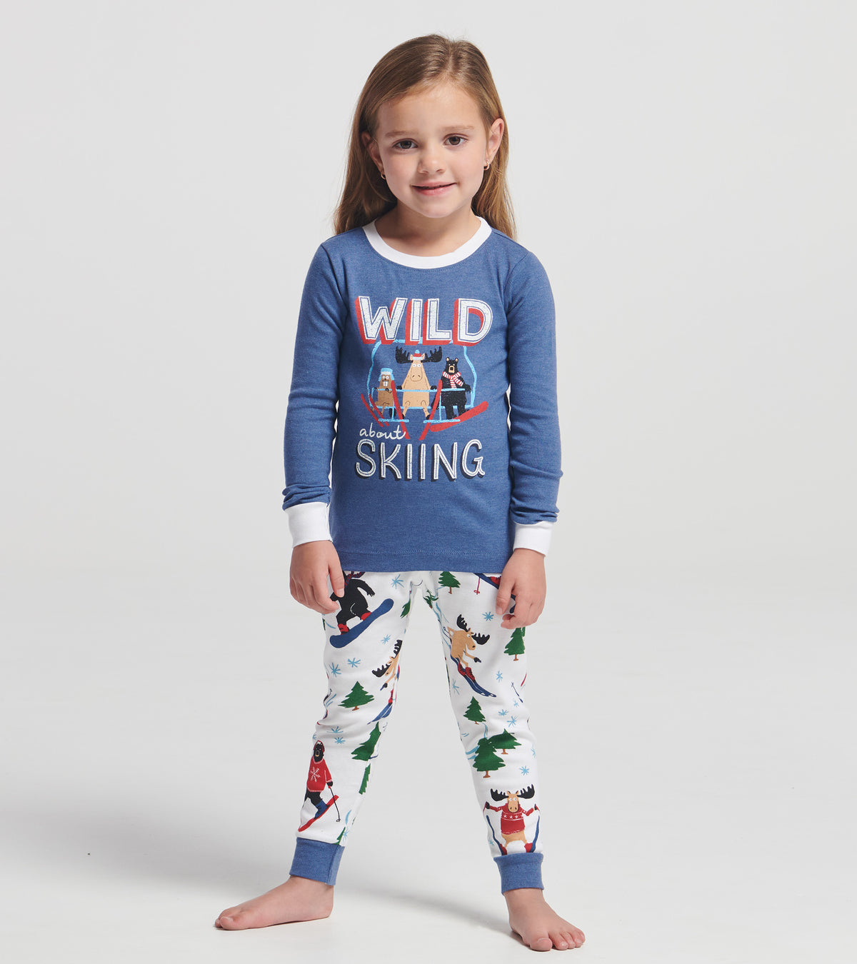Child wearing blue ski-themed pajama set with animal graphic top and white printed pants