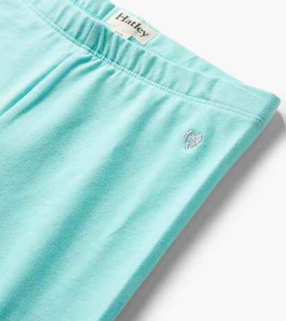 Aqua blue girls bike shorts with elastic waistband and small embroidered heart logo, close-up view
