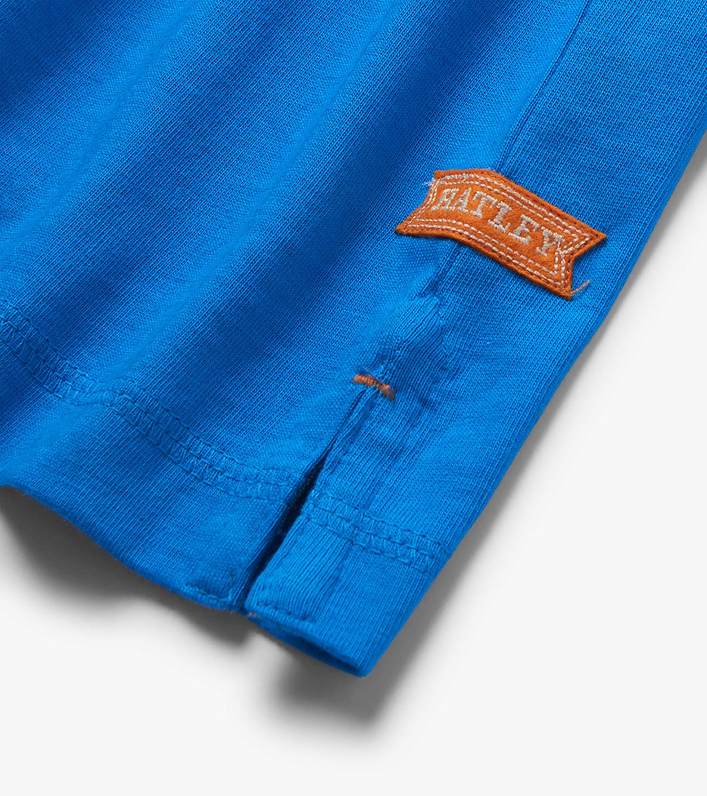 Close-up of a French blue knit T-shirt sleeve hem with orange stitched patch detail