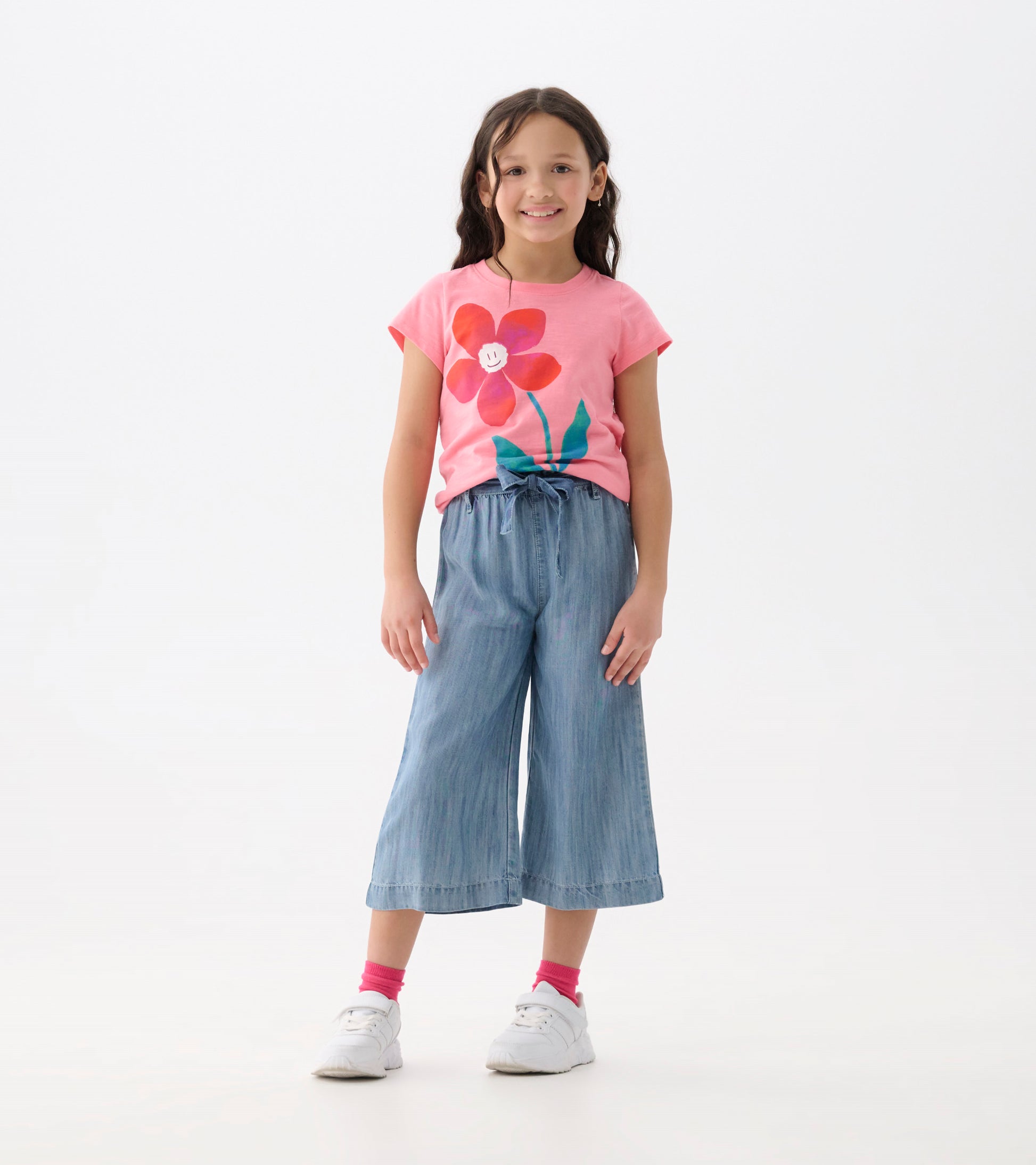 Girls wearing smokey blue cropped paperbag pants with a tie waist, shown front view