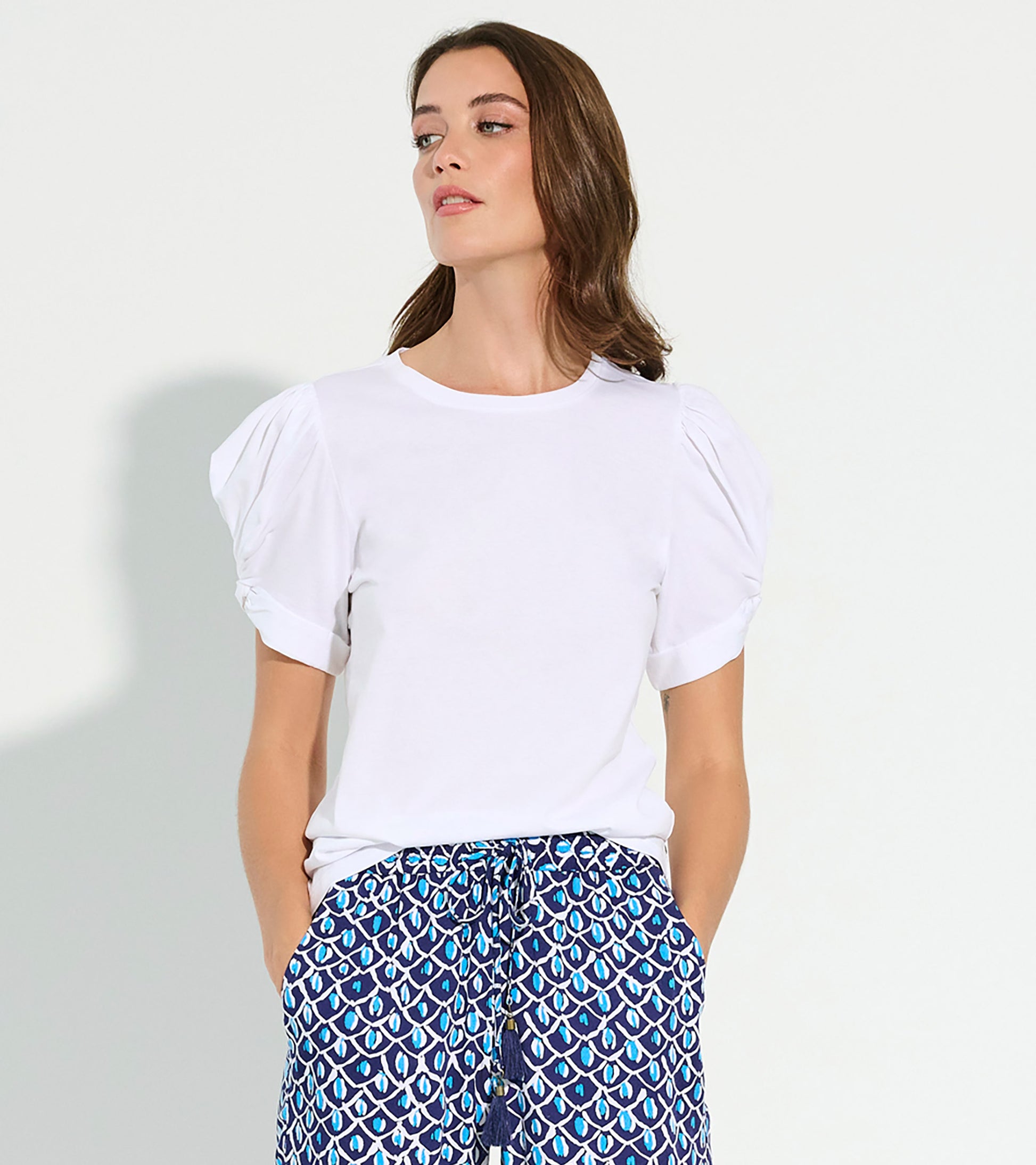 White short-sleeve tee with puffed sleeves, styled with patterned blue and white pants.