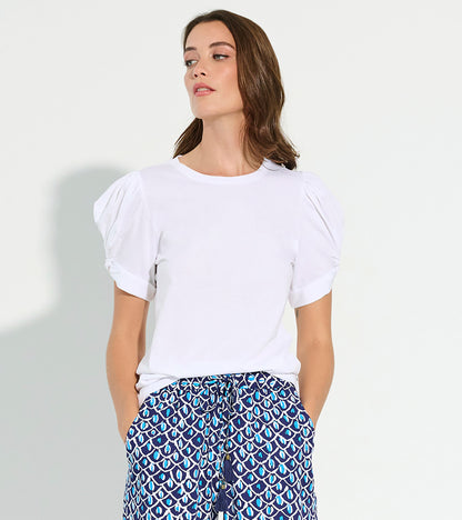 White short-sleeve tee with puffed sleeves, styled with patterned blue and white pants.