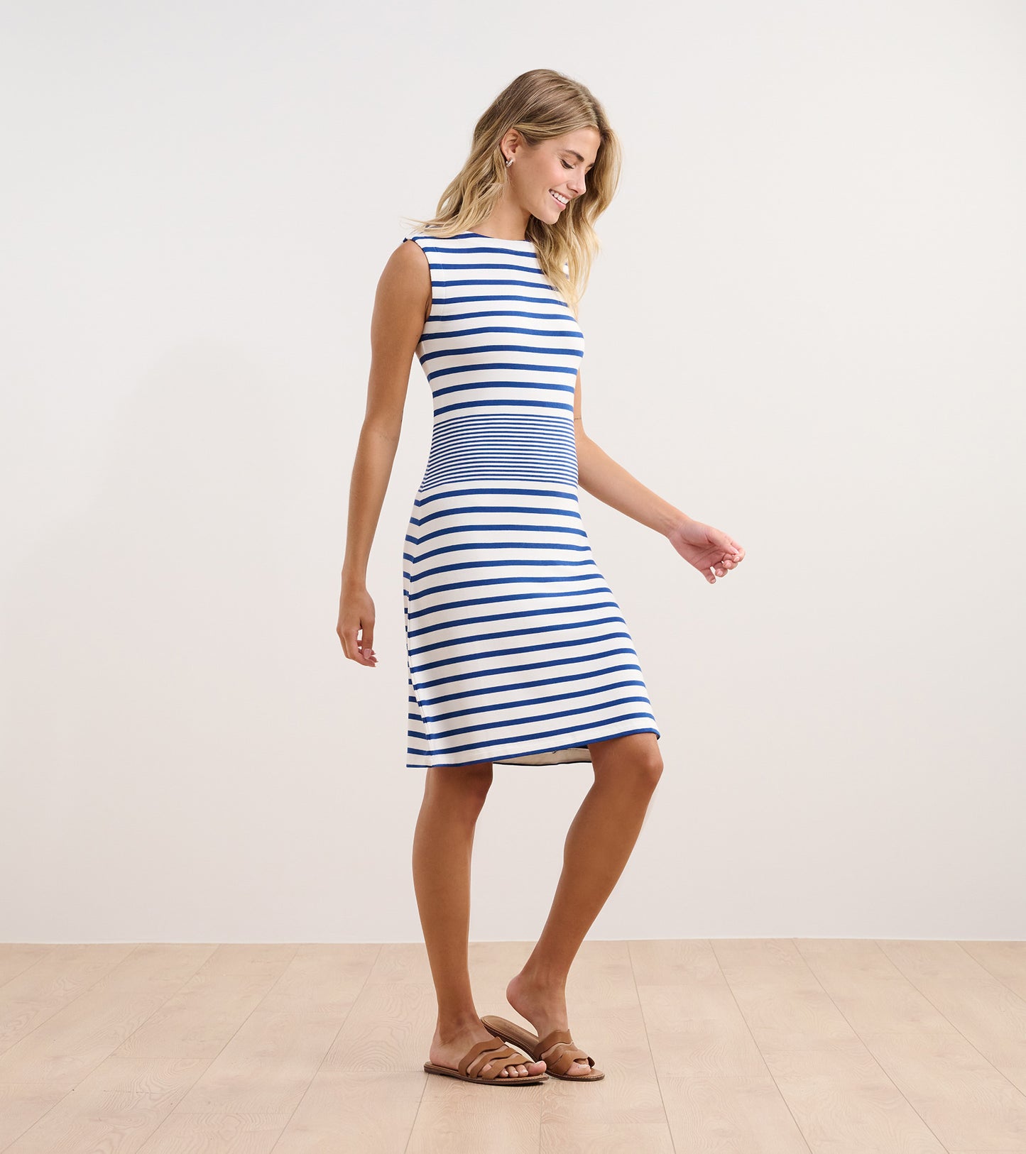 Sleeveless blue and white striped dress with a fitted bodice and flared skirt, styled with flat sandals.