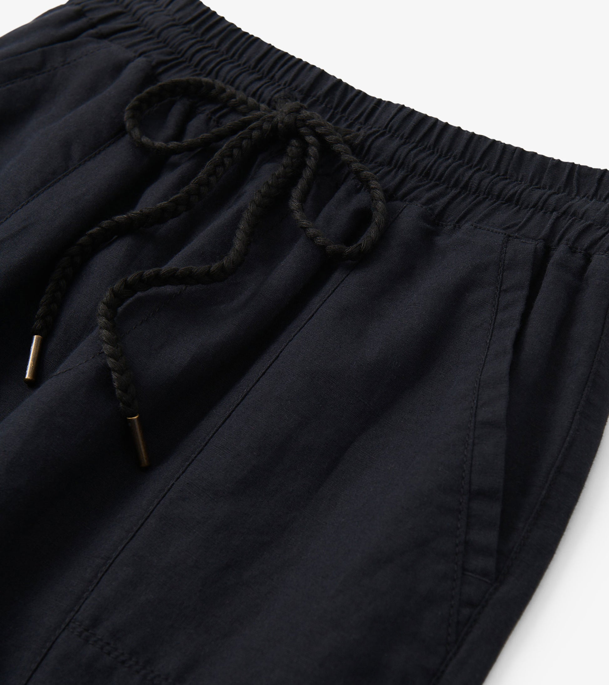 Black linen pants with elastic waistband and braided drawstring, close-up detail view