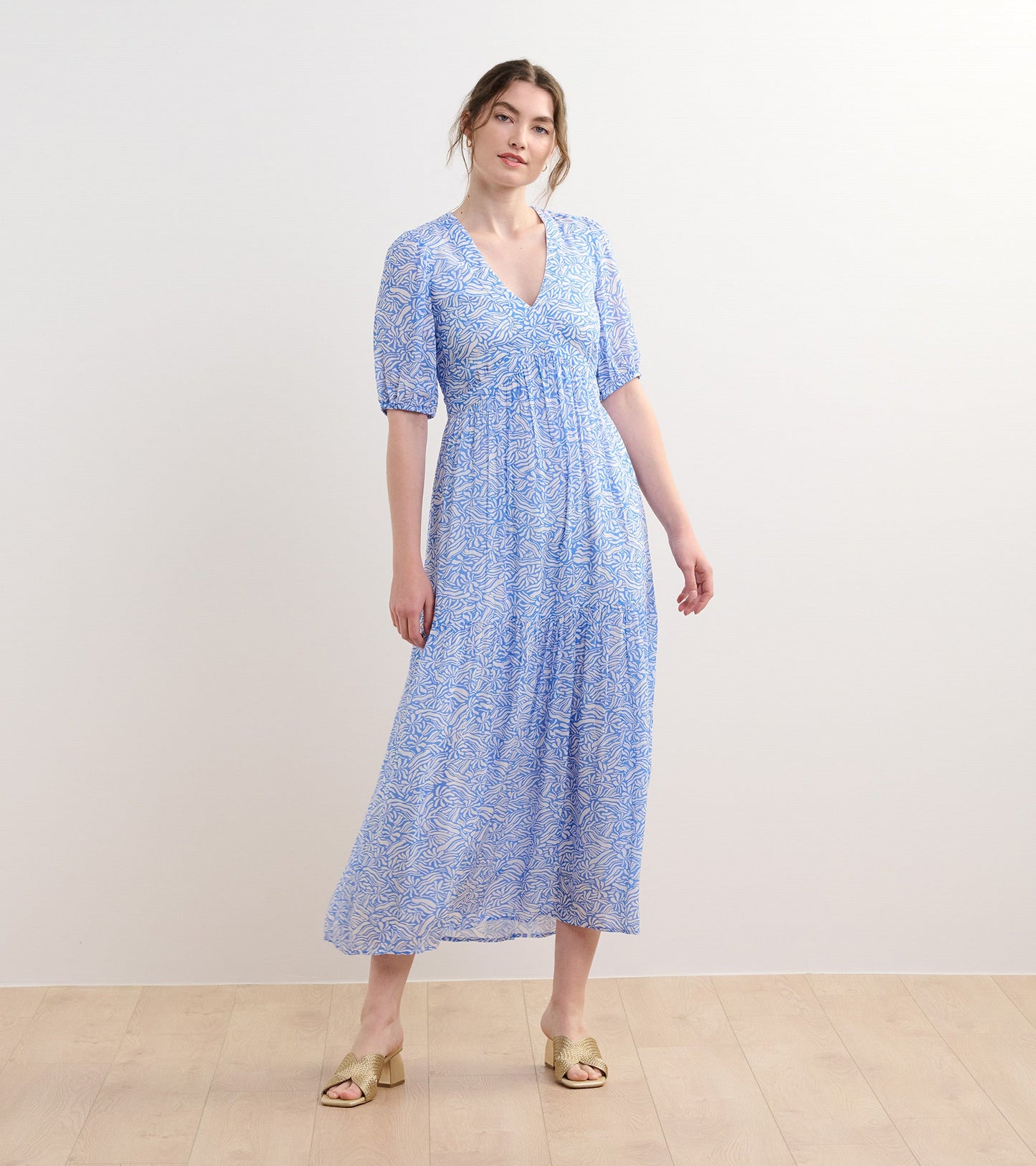 Light blue maxi dress with a floral pattern, short puff sleeves, and a V-neckline, styled with open-toe heels.