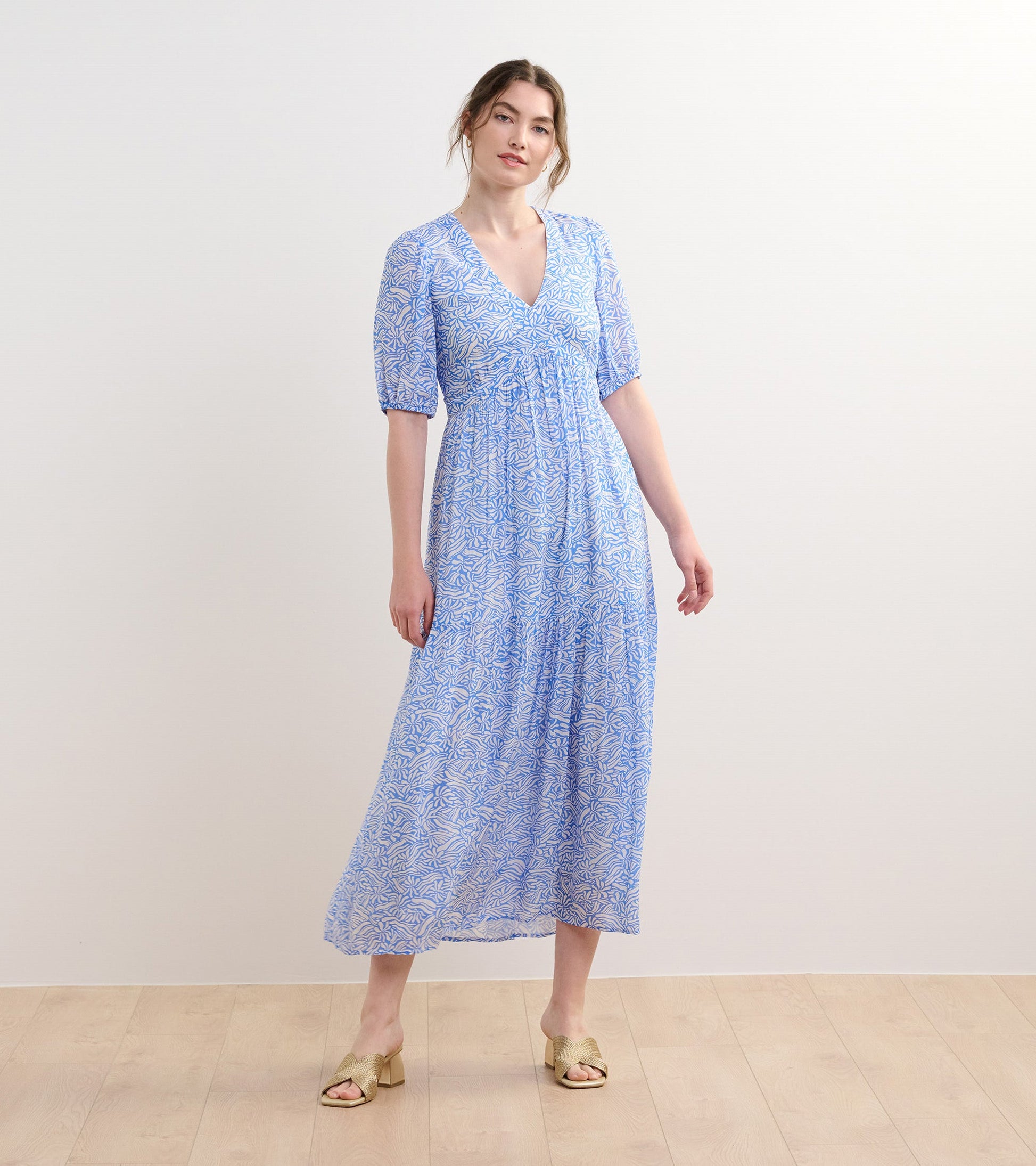 Light blue maxi dress with a floral pattern, short puff sleeves, and a V-neckline, styled with open-toe heels.