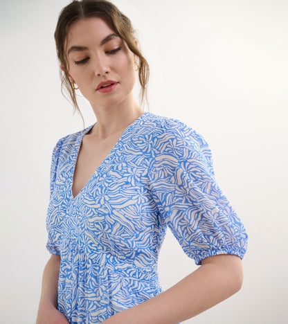 Light blue dress with a groovy floral pattern, featuring a V-neck and puff sleeves, perfect for casual wear.