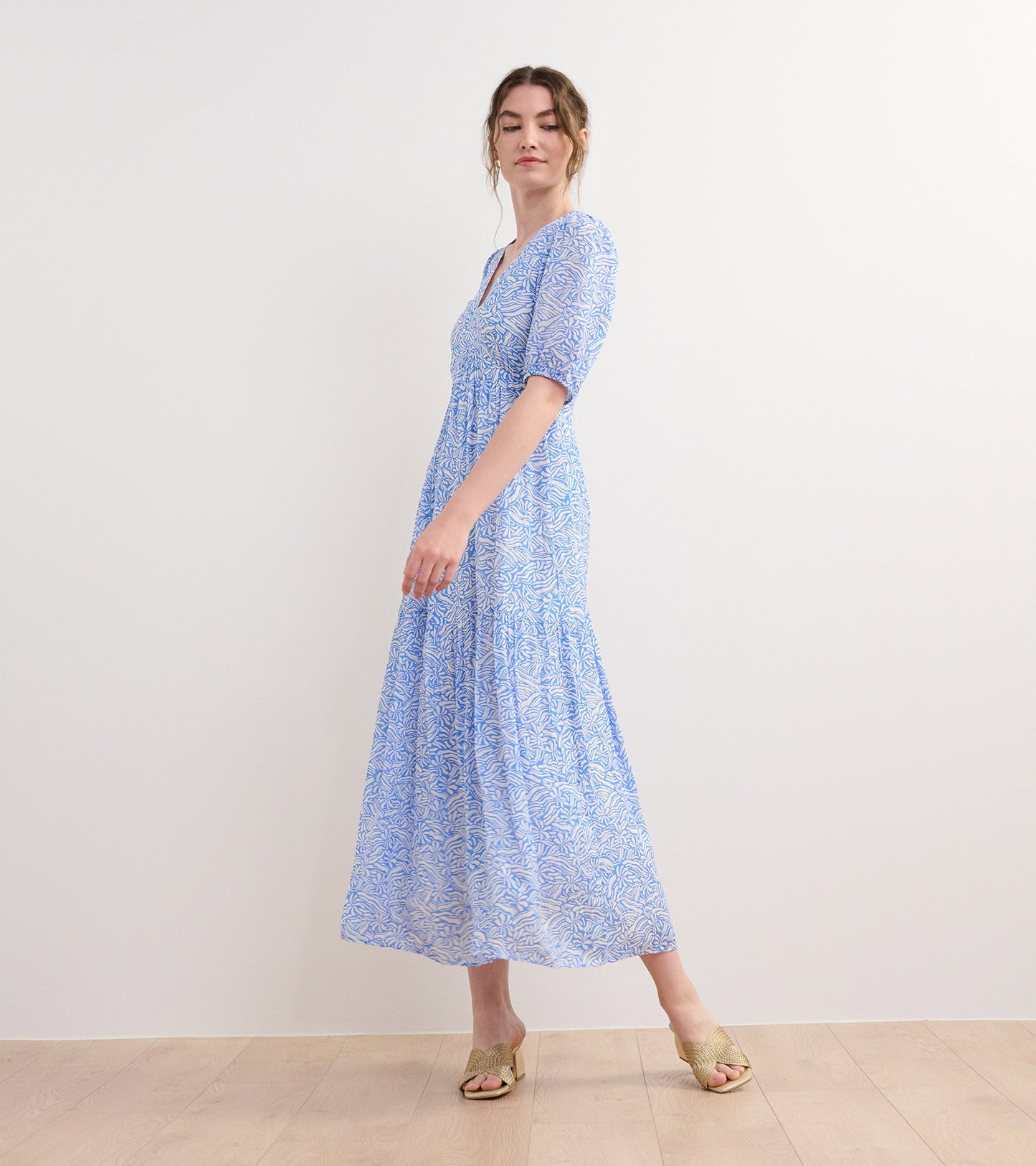 Light blue maxi dress with a groovy floral pattern and short puff sleeves, styled with open-toe heels.