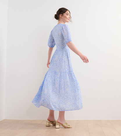 Light blue maxi dress with a groovy floral pattern, featuring puff sleeves and a flowing silhouette.