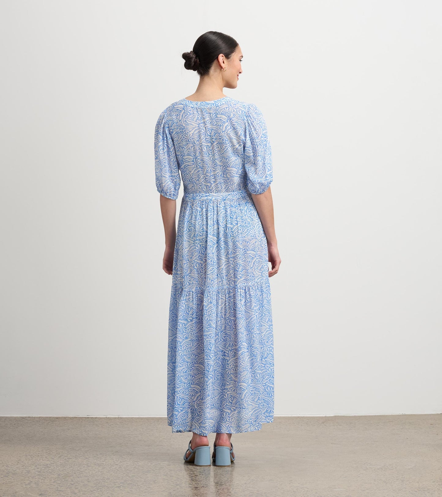 Light blue maxi dress with a groovy floral pattern and puff sleeves, featuring a tiered skirt and a fitted waist.