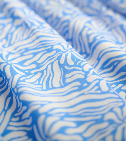 Blue fabric featuring a groovy white floral pattern, showcasing a soft, flowing texture.