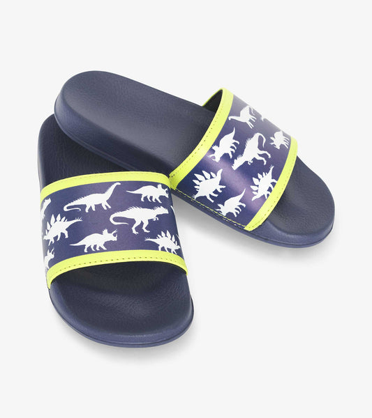 Navy blue slide sandals featuring white dinosaur patterns and bright yellow accents. Ideal for casual wear.