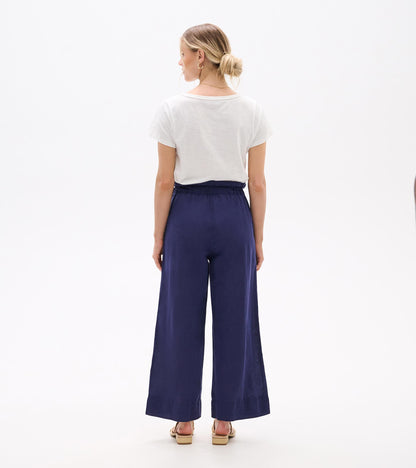 Back view of navy wide-leg pants with a high elastic waist and cropped hem, worn with sandals.