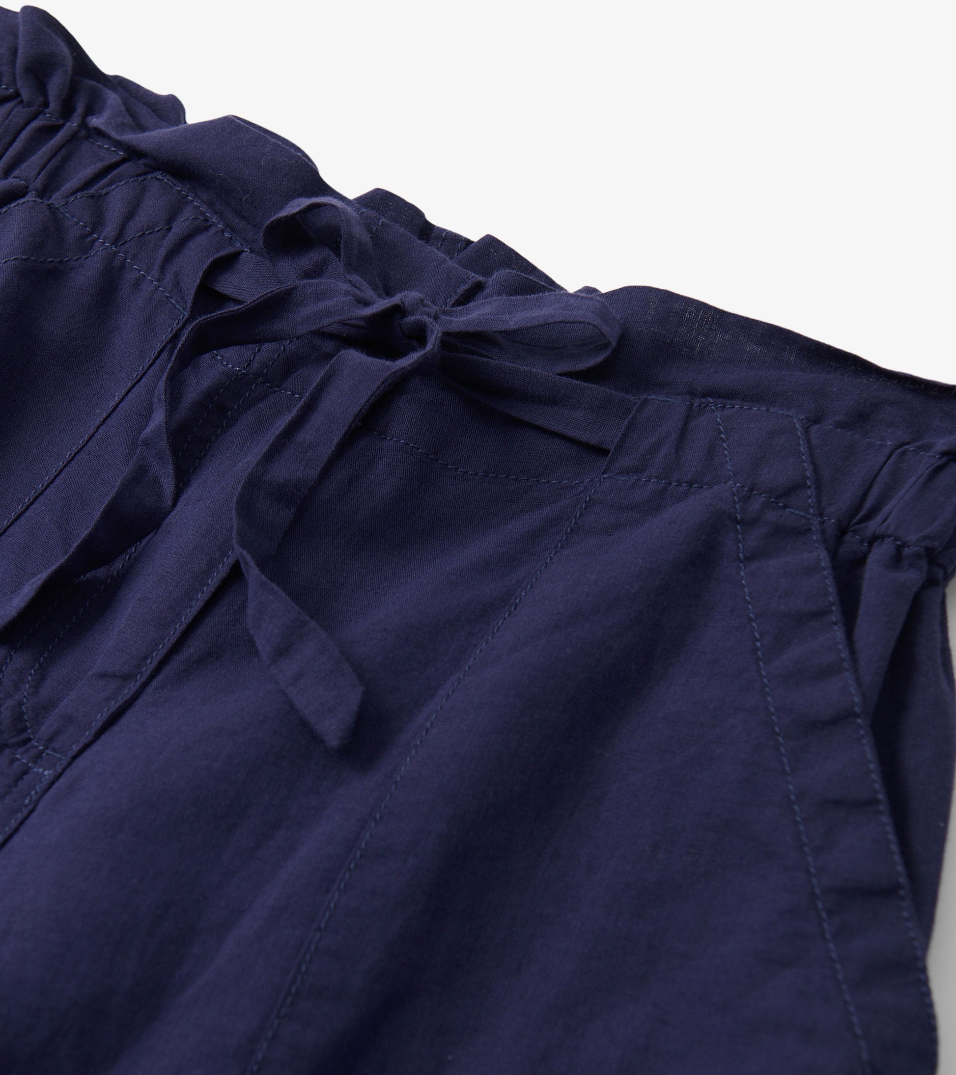 Close-up of navy blue pants with a tie waist and visible stitched seam details