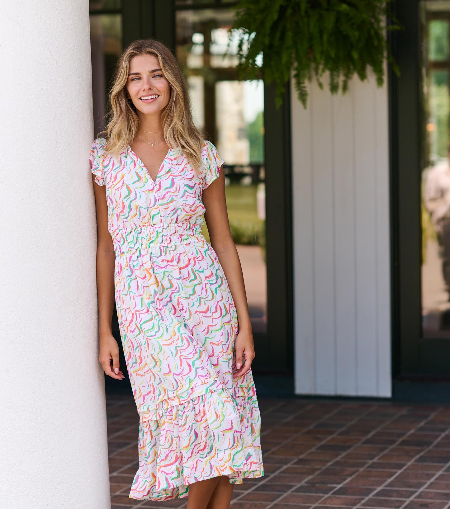 Midi dress featuring wavy stripes in pastel colors, short sleeves, and a smocked waist with a tiered hem.