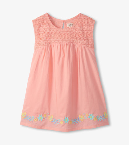 Front view of apricot blush girls dress with crochet bodice, gathered skirt, and embroidered floral hem