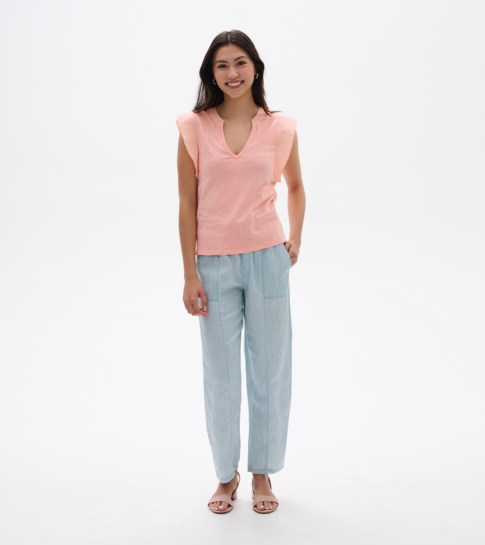 Apricot blush sleeveless V-neck tank top with flutter sleeves, shown on model front view