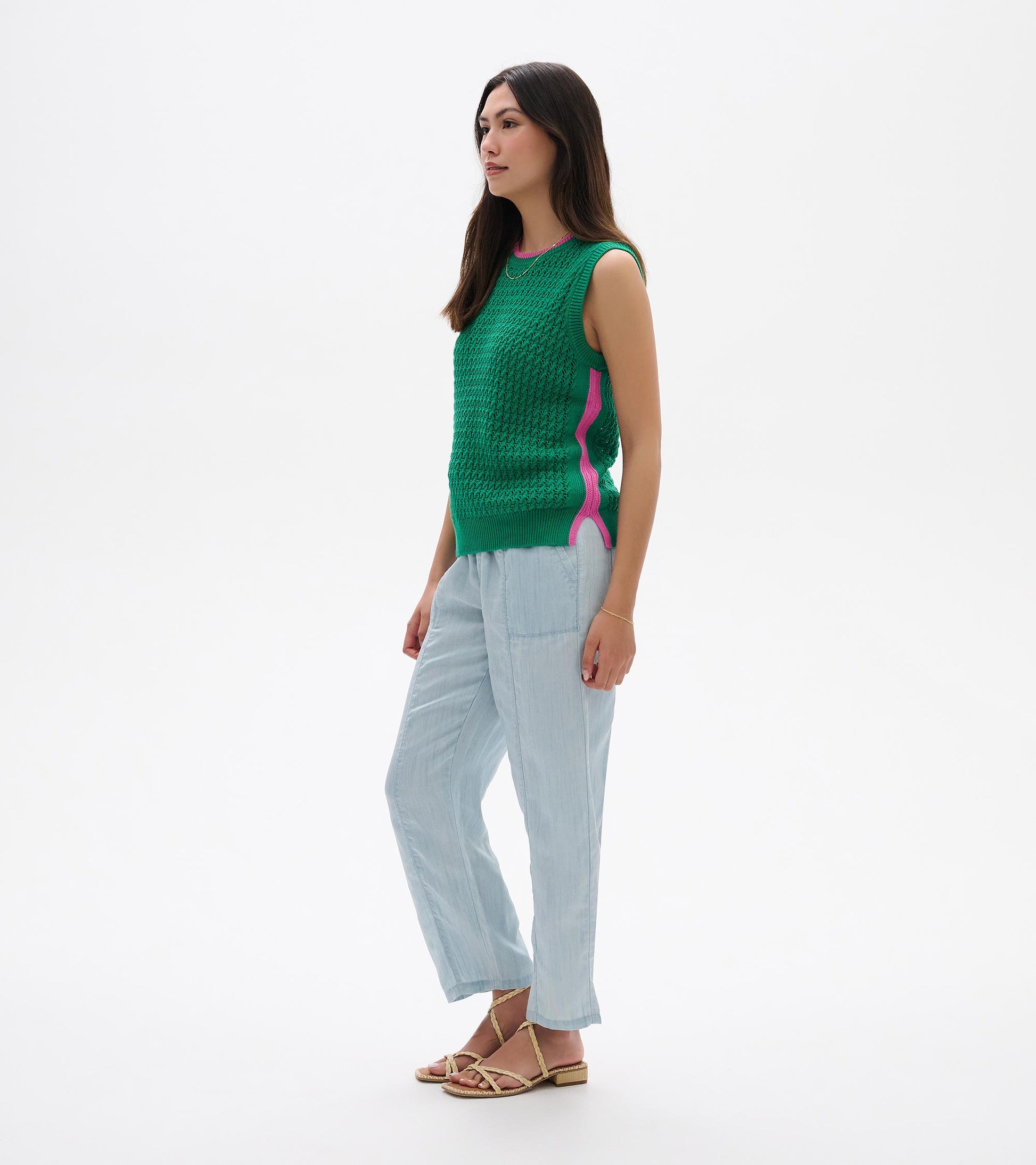 Green knit sleeveless tank top with pink side trim, shown on a model in side view.