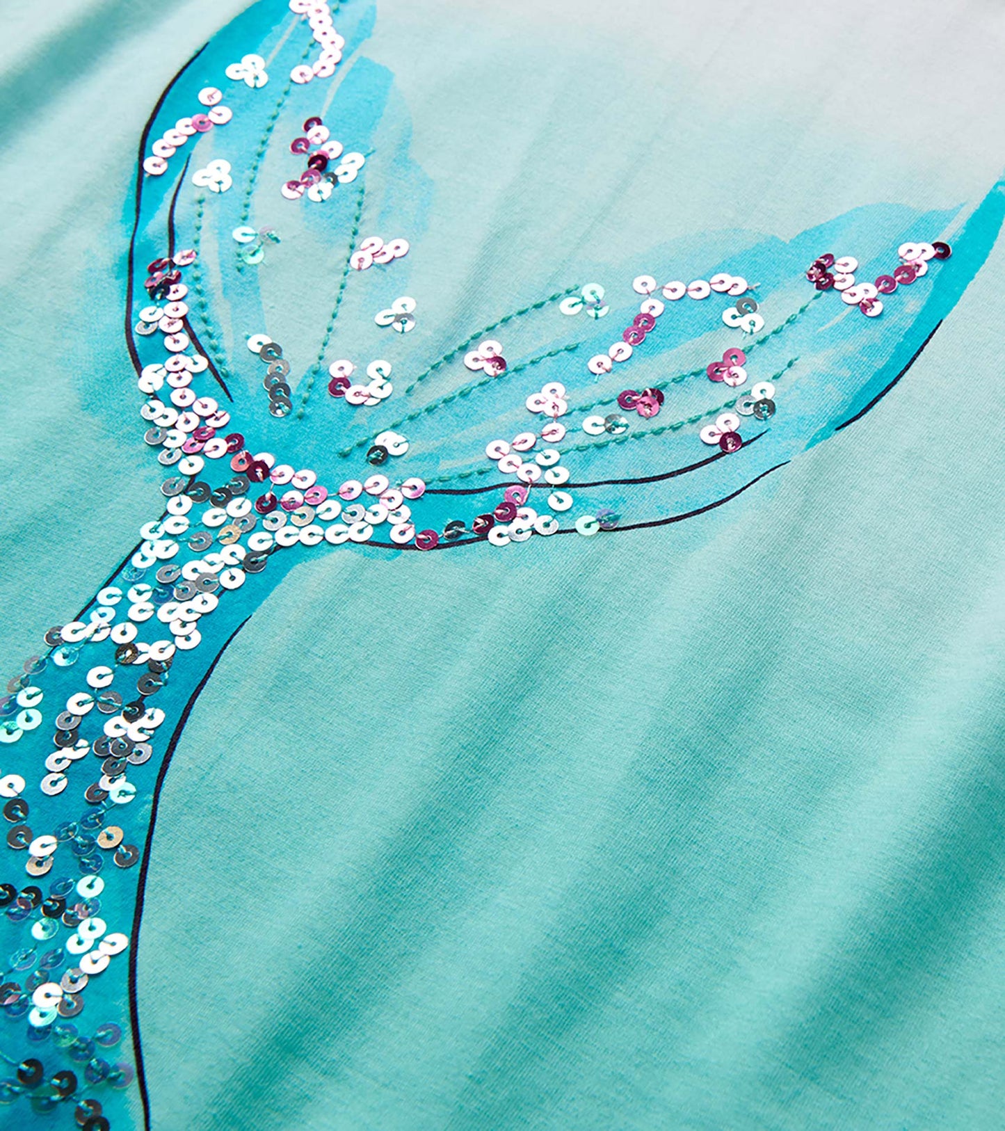 Close-up of a turquoise mermaid tail graphic with iridescent sequins on a light aqua top