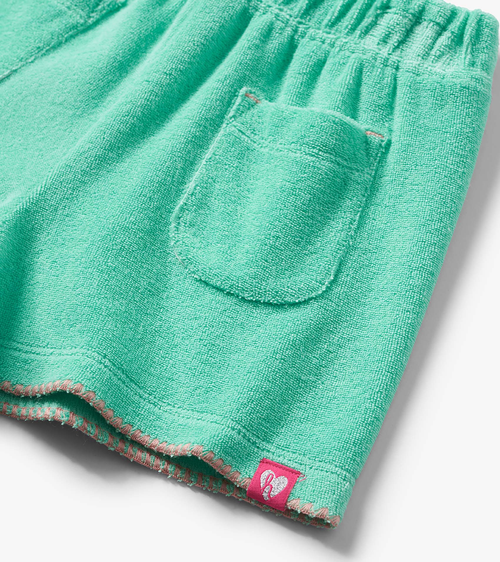 Mint green terry cloth shorts with elastic waistband, back pocket, and pink stitched hem detail