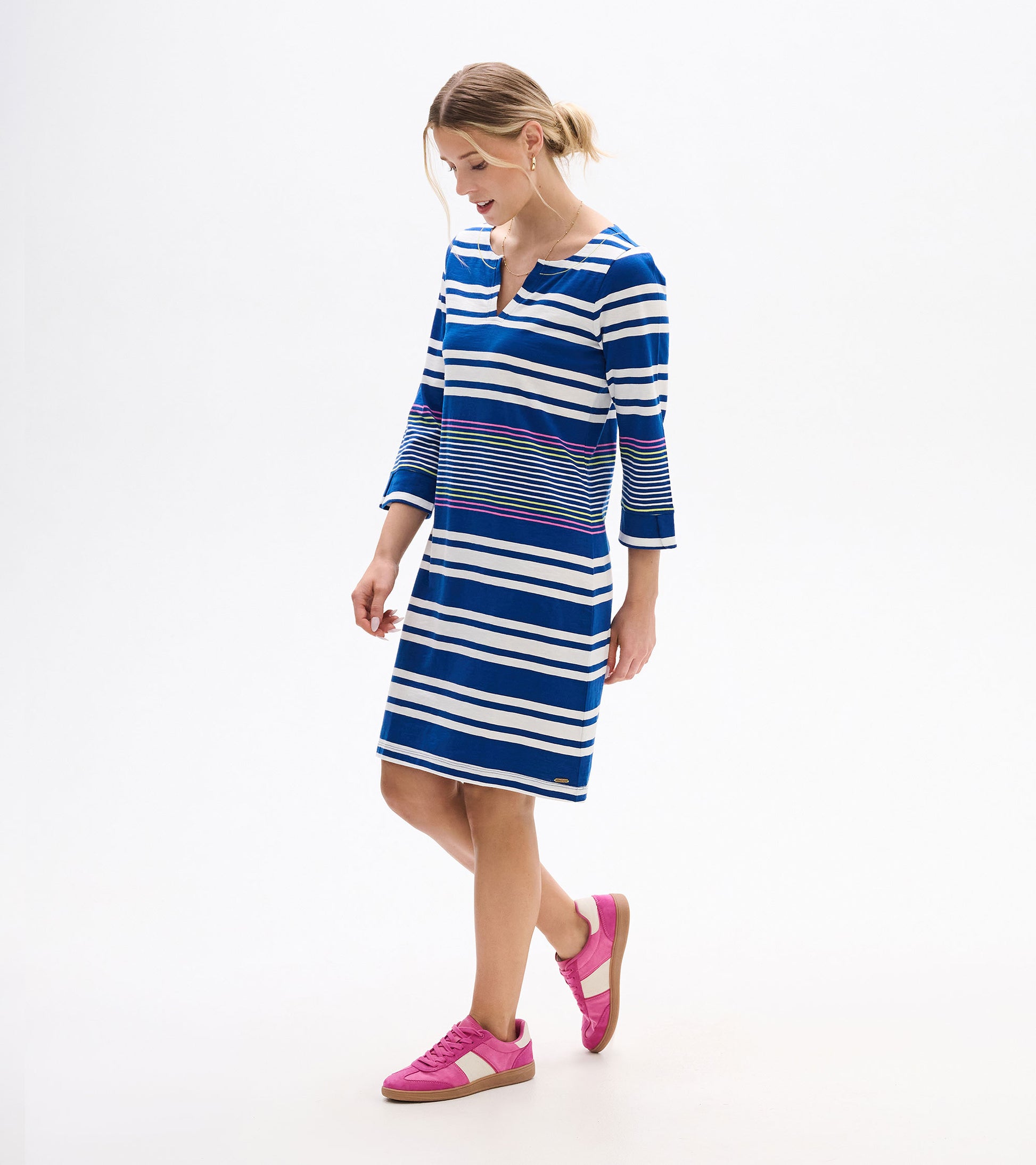 Woman wearing a blue-and-white striped V-neck dress with three-quarter sleeves and pink accent stripes, front view