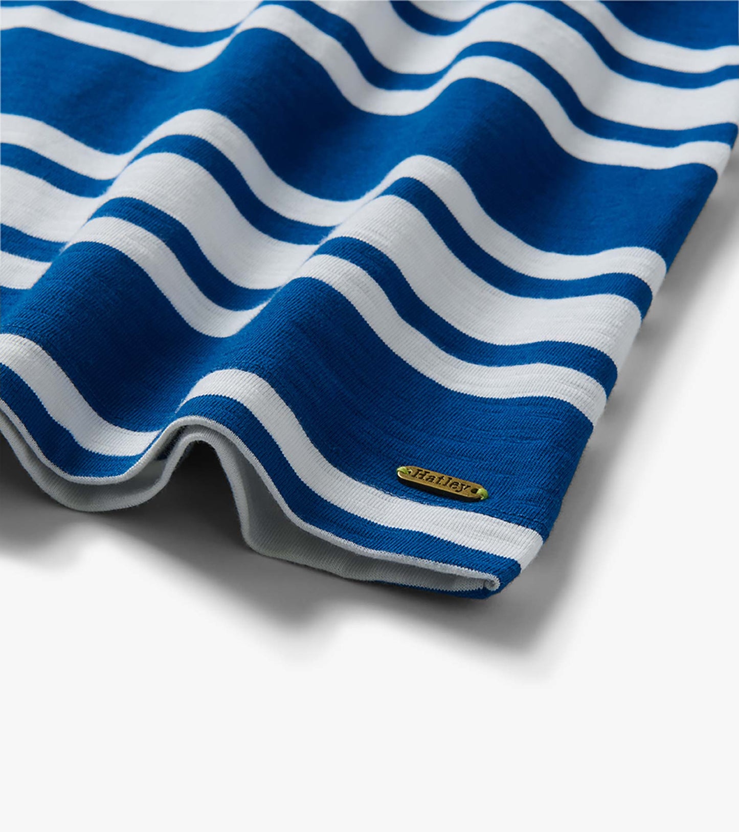 Blue and white striped knit dress hem with small gold logo plaque