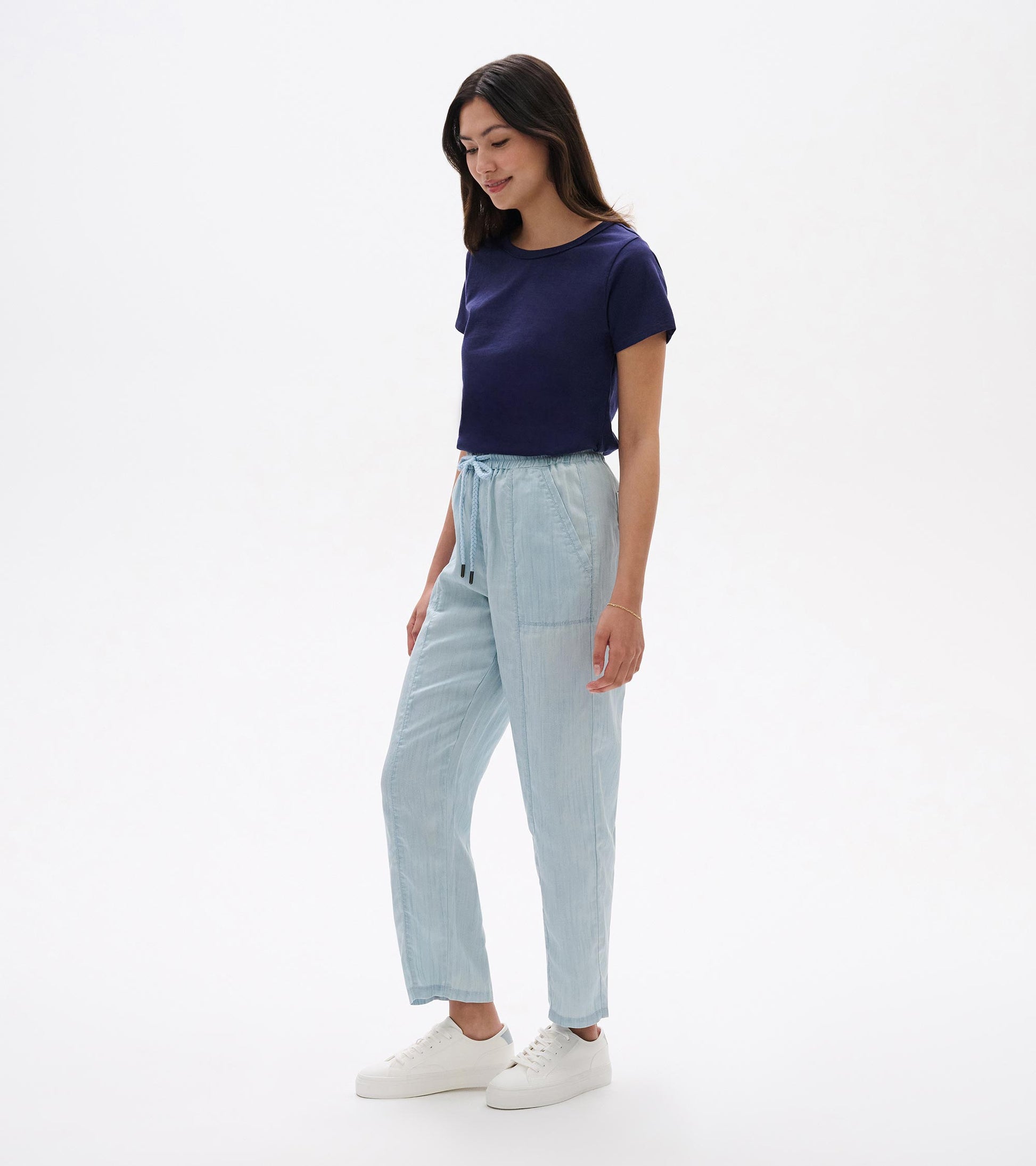Light blue straight-leg pants with an elastic drawstring waist, shown on a model with white sneakers.