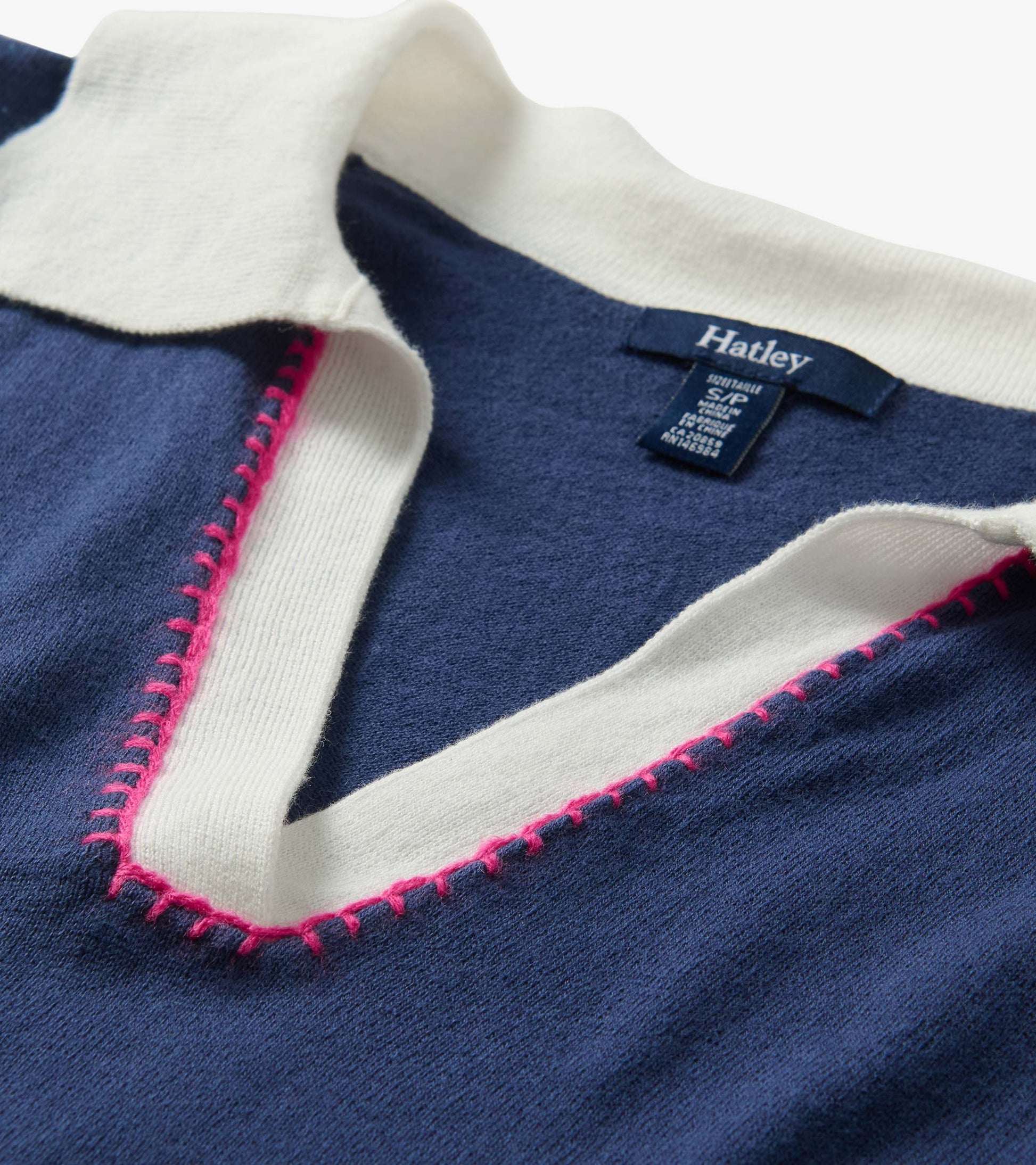 Close-up of a navy knit collared top with white trim and pink contrast stitching, folded neckline detail