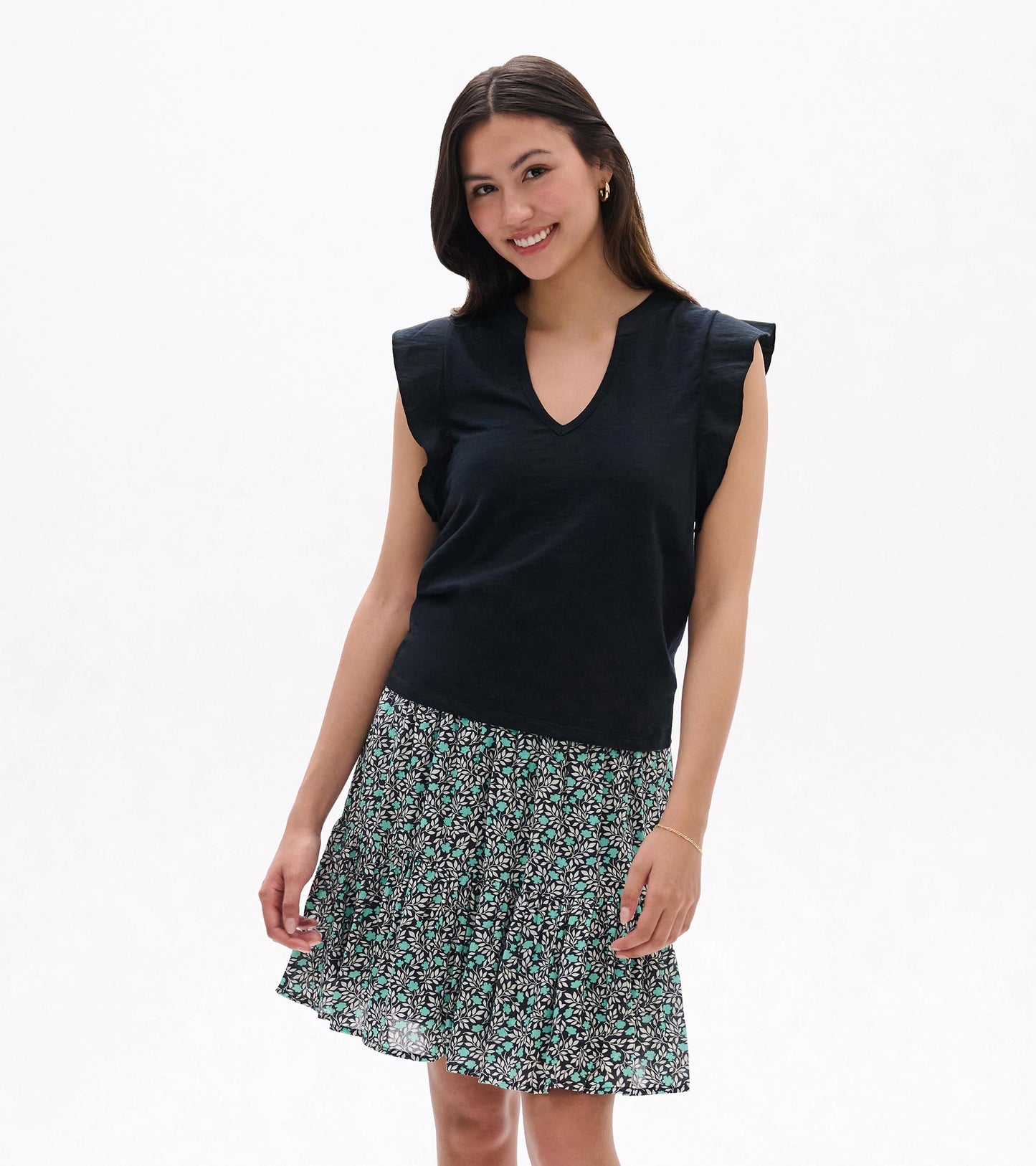 Black sleeveless V-neck top with ruffled shoulders and a floral patterned skirt, front view on model