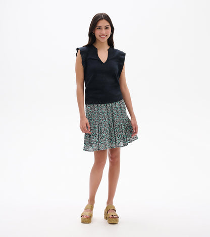 Black sleeveless V-neck top with ruffled shoulders and a teal-and-white floral skirt on a model, front view