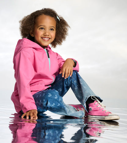 Girl wearing a pink hooded rain jacket with turquoise zipper and blue butterfly-print pants, seated front view