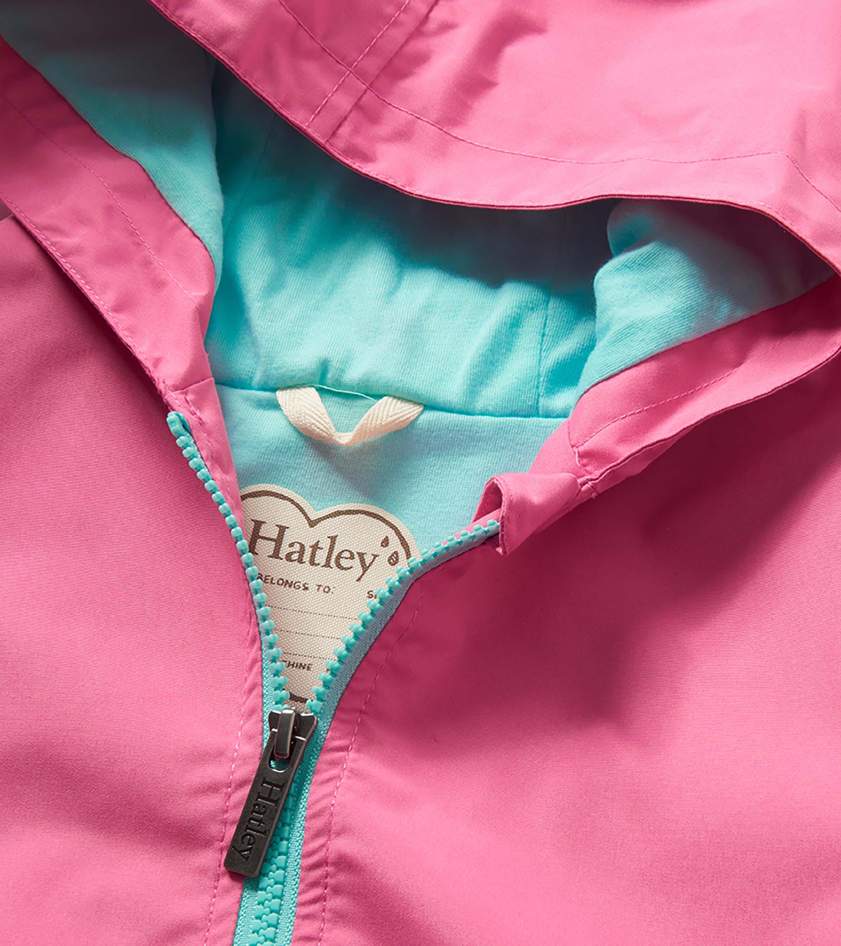Pink girls rain jacket with turquoise lining and zipper, shown in close-up front view.